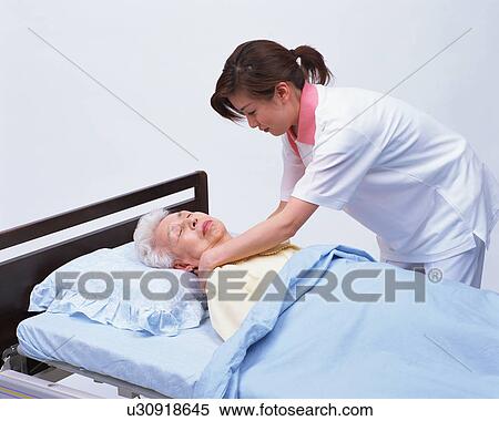 Stock Photography - A senior woman in a bed and a caretaker. Fotosearch