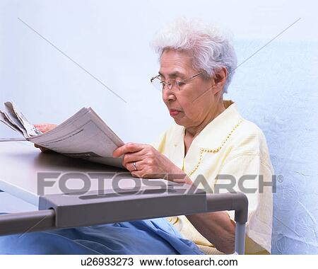A senior woman in a bed reading newspaper View Large Photo Image Stock Image - A senior woman in a bed reading newspaper. Fotosearch