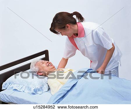 A senior woman in a bed talking with caretaker View Large Photo Image Stock Image - A senior woman in a bed talking with caretaker. Fotosearch