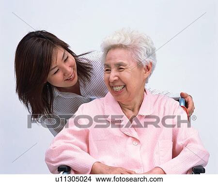 Picture - A senior woman in a wheel chair talking with her grand daughter. Fotosearch