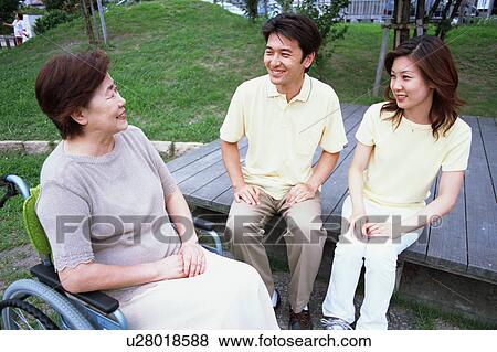 Stock Photo - A senior woman in a wheel chair talking with her children. Fotosearch