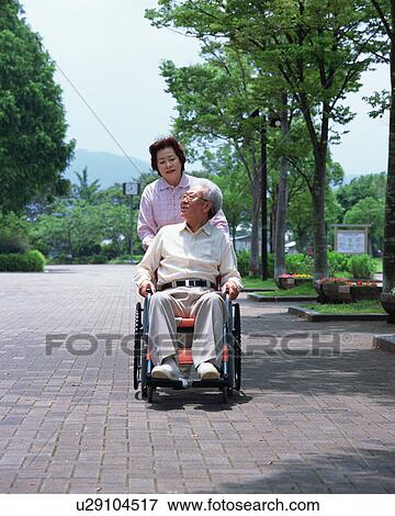 A senior woman pushing a senior man in a wheel chair View Large Photo Image Stock Photo - A senior woman pushing a senior man in a wheel chair. Fotosearch