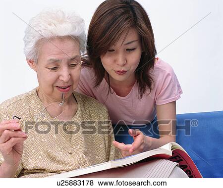 Stock Photo - A senior woman reading a book with her granddaughter. Fotosearch