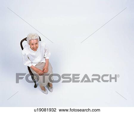 Stock Image - A senior woman sitting in a chair. Fotosearch
