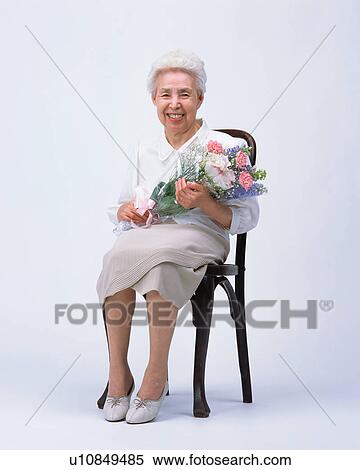 Stock Photography - A senior woman sitting in a chair with flower bouquet. Fotosearch