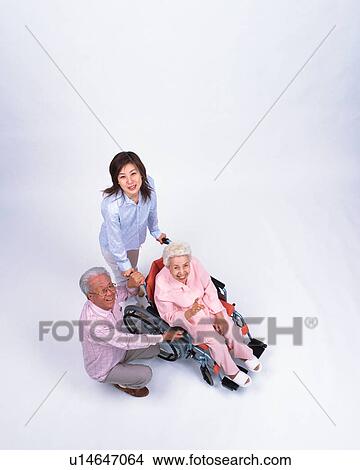 Picture - A young woman pushing a senior woman in a wheel chair. Fotosearch