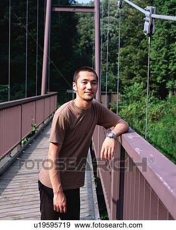Stock Photo - A young man leaning to a bridge. Fotosearch