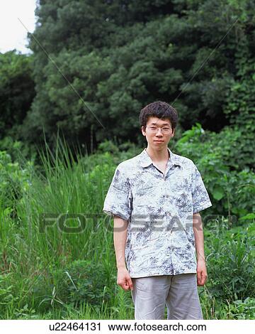 A young man standing in fields View Large Photo Image Stock Image - A young man standing in fields. Fotosearch