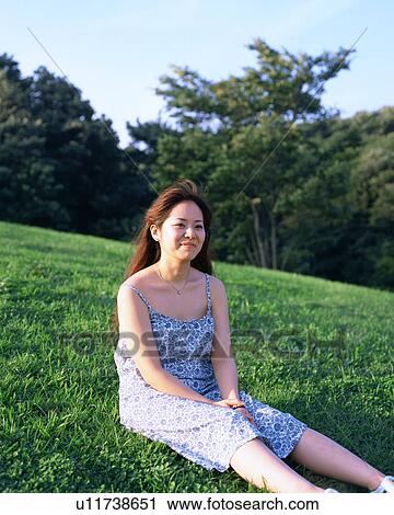 Stock Image - A young woman sitting in fields. Fotosearch