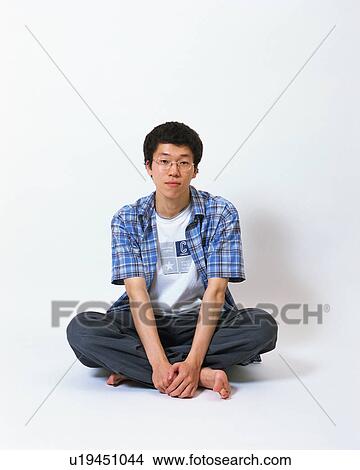 Picture - Portrait of a young man sitting with his legs crossed. Fotosearch