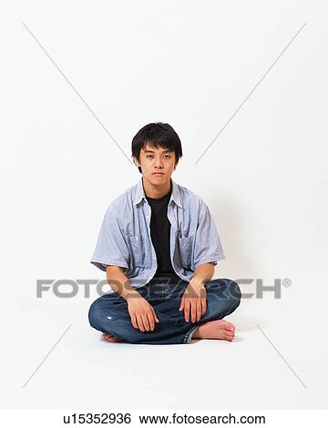 Stock Photograph - Portrait of a young man sitting with his legs crossed. Fotosearch