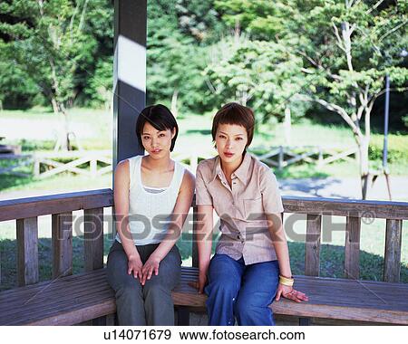 Stock Photo - Two young woman sitting and looking at camera. Fotosearch