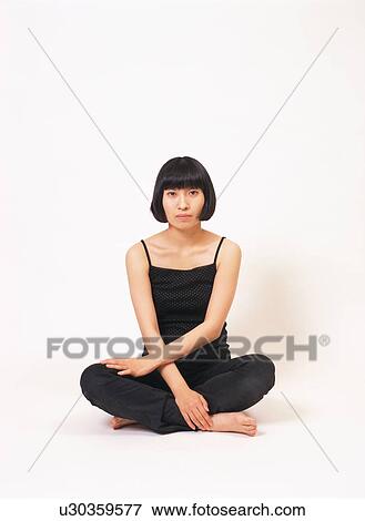 Stock Photo - A young woman sitting with her legs crossed. Fotosearch