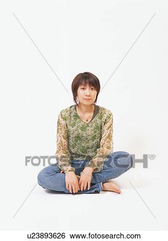 Stock Photograph - A young woman sitting with her legs crossed. Fotosearch