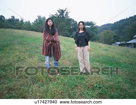 Stock Image - Two young women standing in fields. Fotosearch