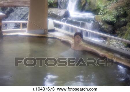 Stock Image - A young woman bathing in hot springs. Fotosearch