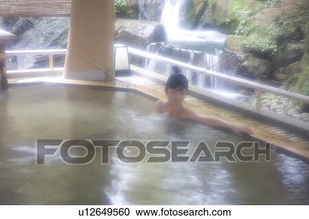 Stock Image - A young woman bathing in hot springs. Fotosearch