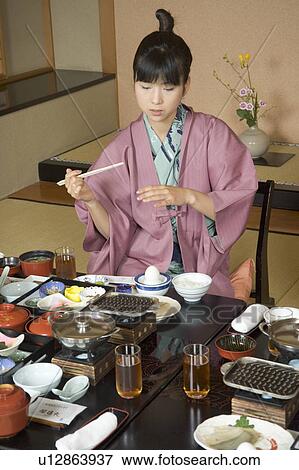 Stock Photo - A young woman eating dinner in Japanese style inn. Fotosearch