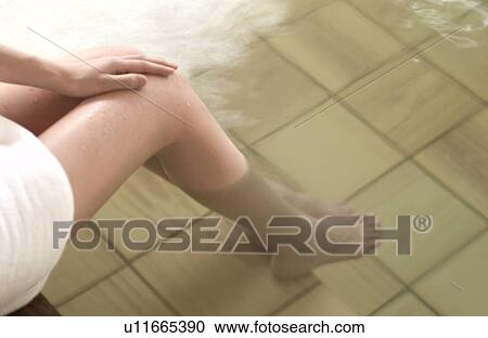 Stock Image - Low section of a woman bathing in hot springs. Fotosearch