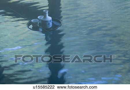 Stock Image - Sake bottle floating on hot water. Fotosearch