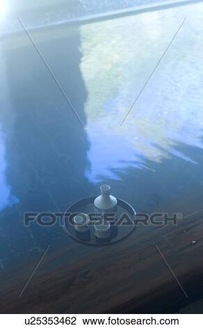 Stock Image - Sake bottle floating on hot water. Fotosearch
