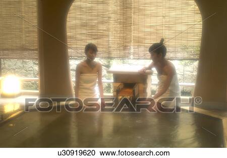 Stock Image - Two young women bathing in hot springs. Fotosearch