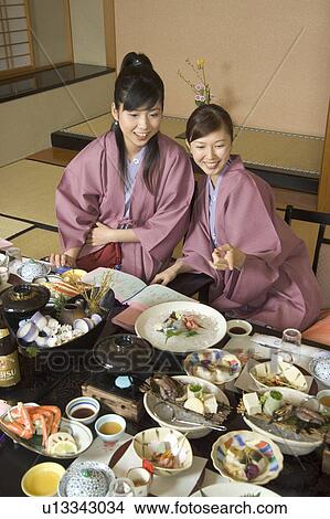 Picture - Two young women eating dinner in Japanese style inn. Fotosearch
