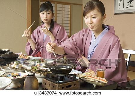 Picture - Two young women eating dinner in Japanese style inn. Fotosearch