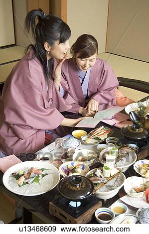 Stock Photo - Two young women eating dinner in Japanese style inn. Fotosearch