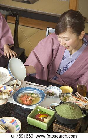 Stock Photo - Two young women eating dinner in Japanese style inn. Fotosearch
