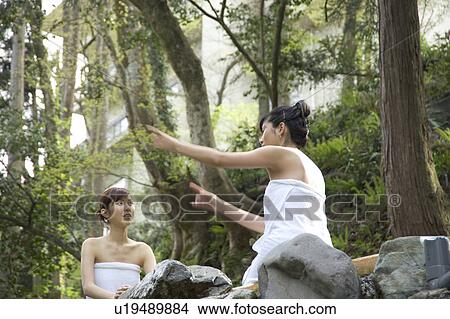 Picture - Two young women talking in hot springs. Fotosearch