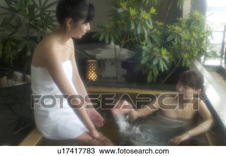 Stock Image - Two young women talking in hot springs. Fotosearch