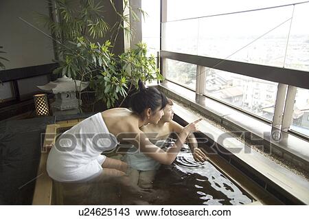 Stock Image - Two young women talking in hot springs. Fotosearch