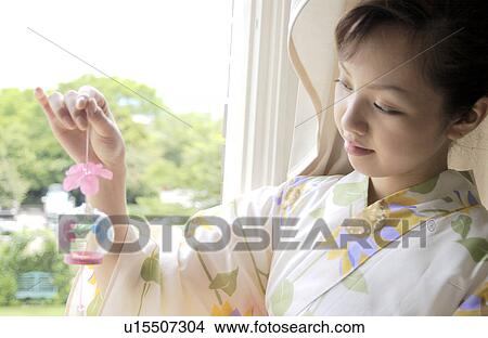 Picture - A woman holding wind chime. Fotosearch