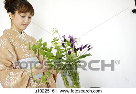 Stock Image - A woman in kimono arranging flowers. Fotosearch