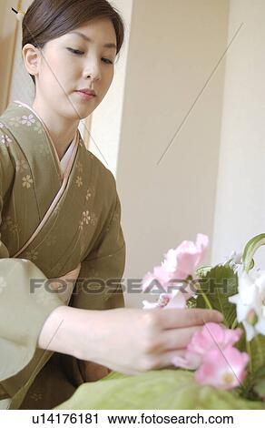 Stock Image - A woman in kimono arranging flowers. Fotosearch