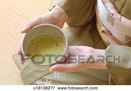 Stock Photo - A woman in kimono holding a cup of green tea. Fotosearch