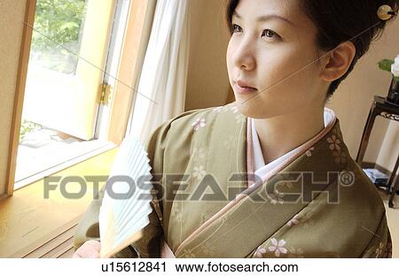 Stock Image - A woman in kimono holding fan. Fotosearch