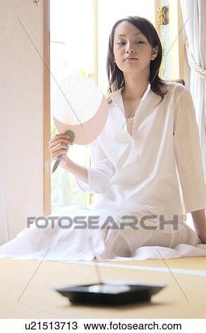 Stock Image - A woman sitting with fan. Fotosearch