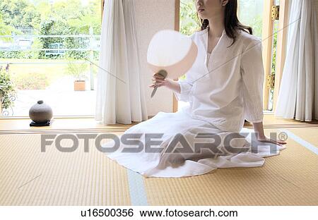 Stock Photograph - A woman sitting with fan. Fotosearch