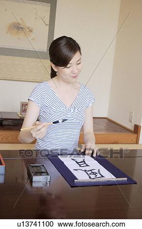 Stock Image - A woman writing letters with ink brush. Fotosearch