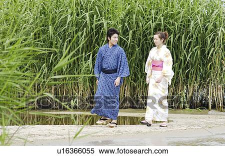 Stock Photography - A young couple in kimono walking on lake side. Fotosearch