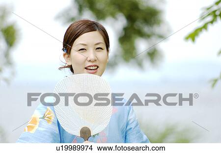 A young woman in kimono smiling with fan View Large Photo Image Picture - A young woman in kimono smiling with fan. Fotosearch