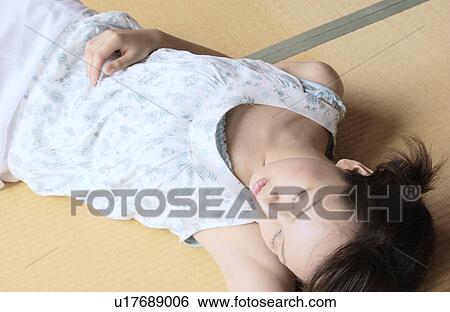 Stock Photograph - A young woman taking a nap in tatami room. Fotosearch
