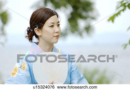 Stock Photograph - Portrait of a young woman in kimono holding fan. Fotosearch