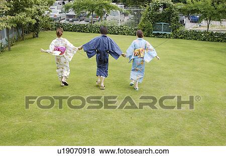 Stock Photo - Three people in kimono holding hands. Fotosearch