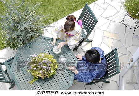 Stock Photo - Two people in kimono sitting at outdoor table. Fotosearch