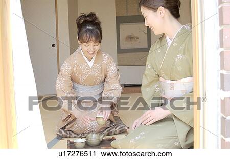 Stock Image - Two women in kimono serving tea. Fotosearch