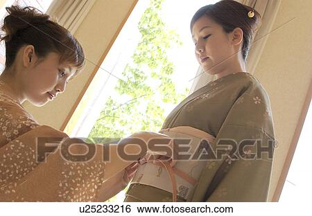 Two women tying obi sash View Large Photo Image Stock Photograph - Two women tying obi sash. Fotosearch