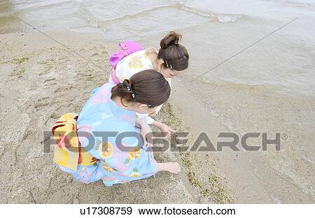 Stock Photo - Two young women in kimono sitting on lake side. Fotosearch